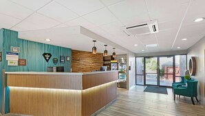 Een receptie met een houten balie, wanden in een blauwgroene kleur en een modern interieur.