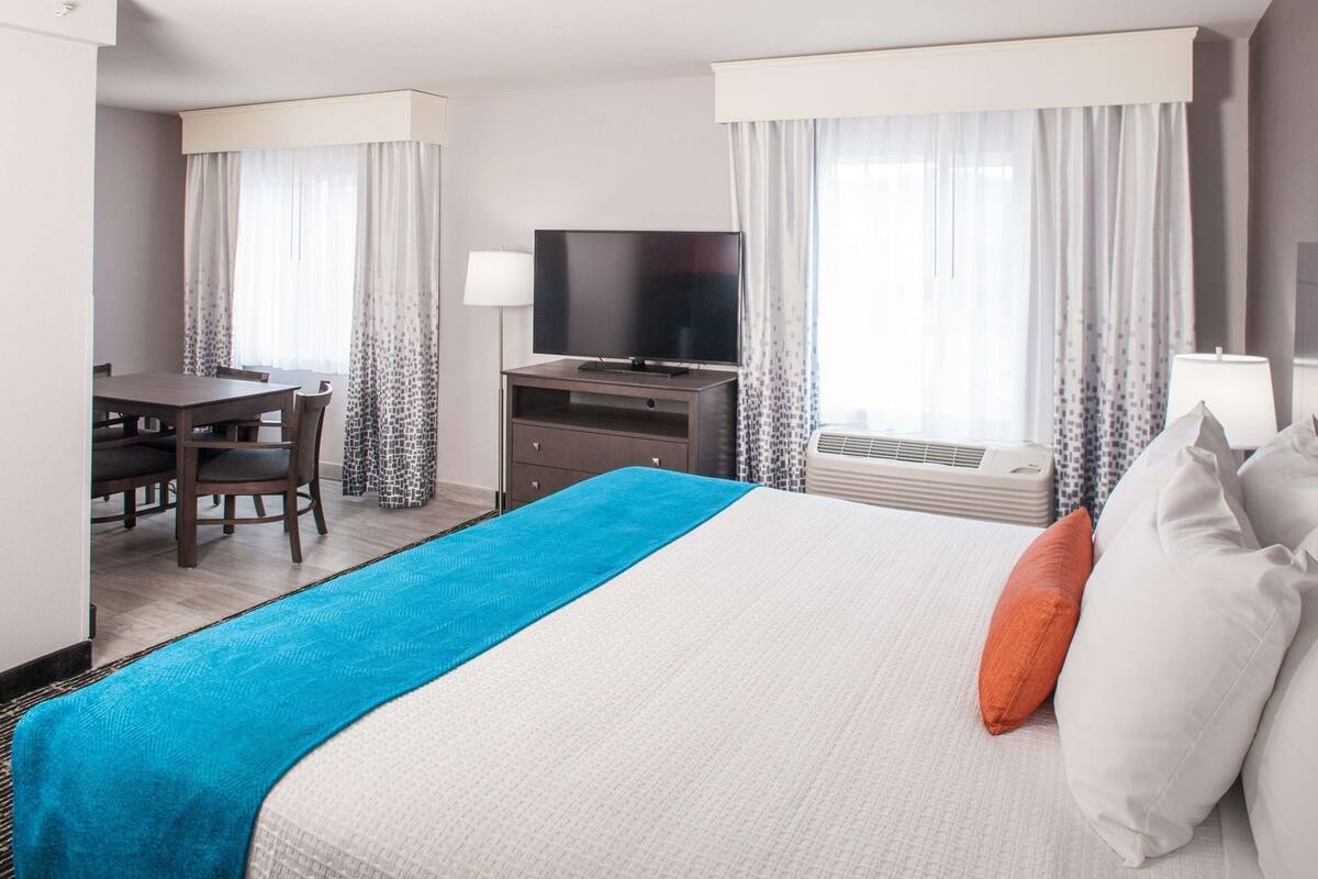Ein Hotelzimmer mit einem Bett, einem Schreibtisch, einem Fernseher und Vorhängen.