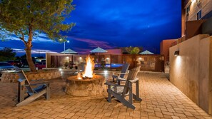An outdoor patio with a fire pit, lounge chairs, and a swimming pool in the background. - Best Western Plus Sun Canyon (Sierra Vista)