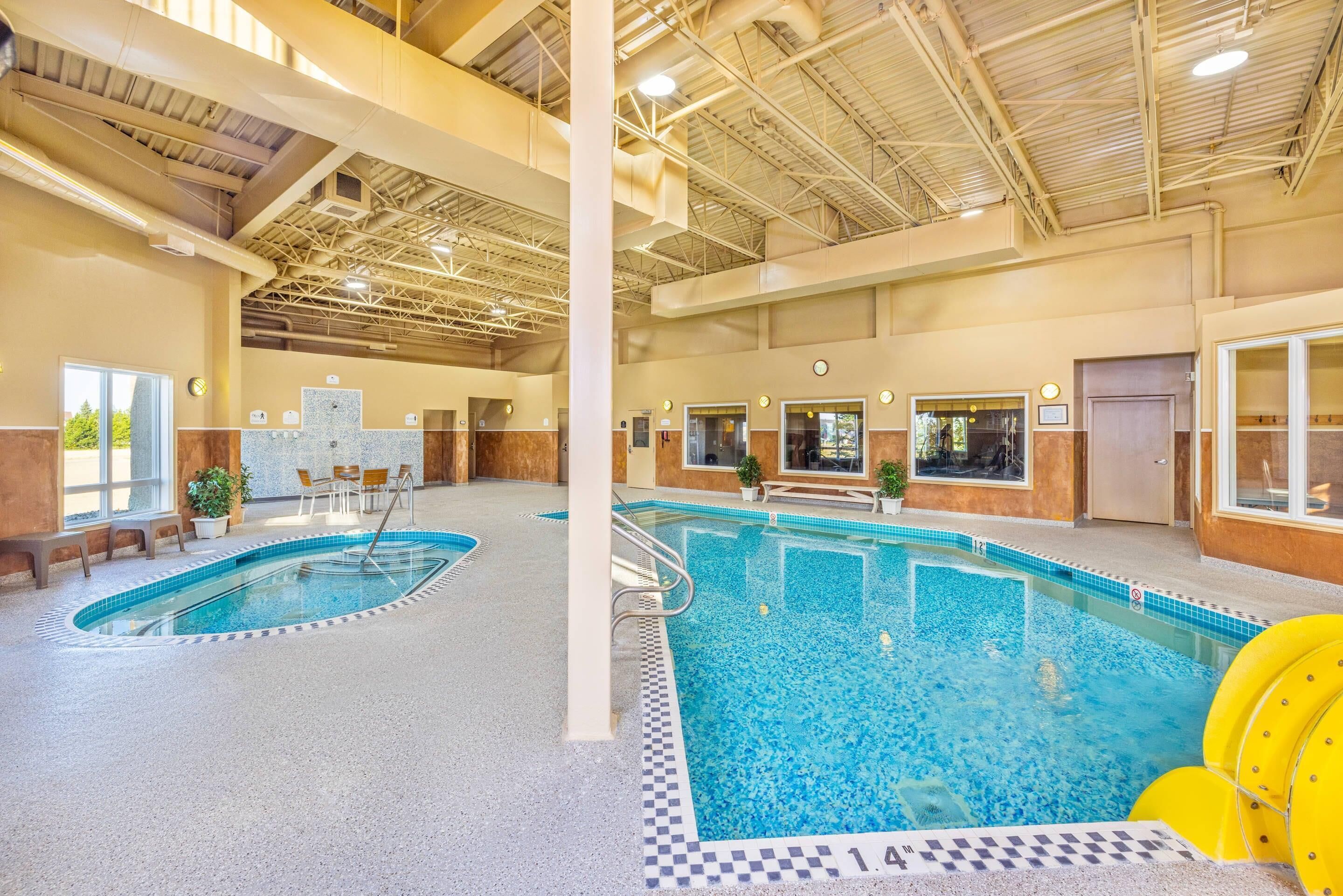 An indoor swimming pool with multiple lanes, a lifeguard chair, and a yellow floatation device.