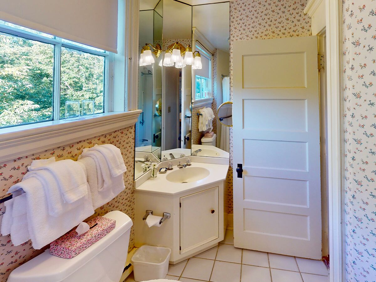 Un baño con ventana, lavabo, inodoro y puerta.