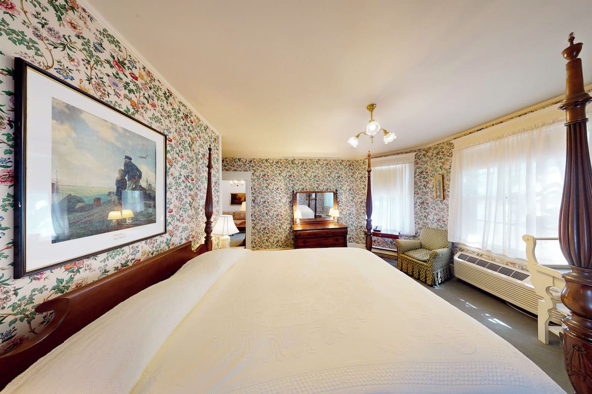 A hotel room with a large bed, a dresser, a mirror, and a window with curtains.