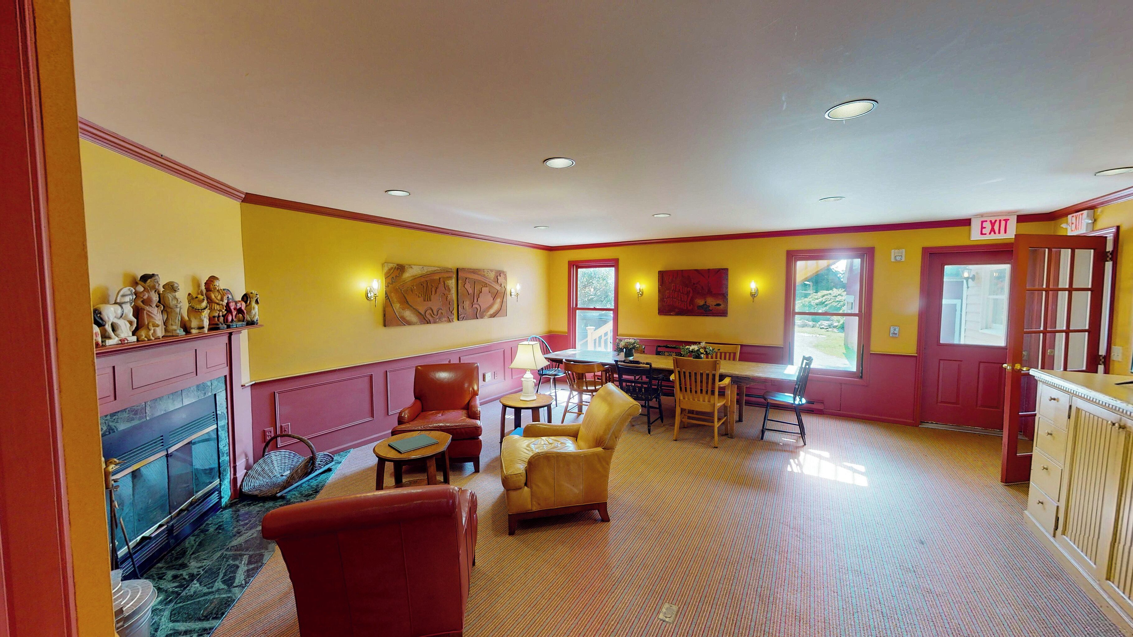 A dining area with a table and chairs, a fireplace, and a window with a view.