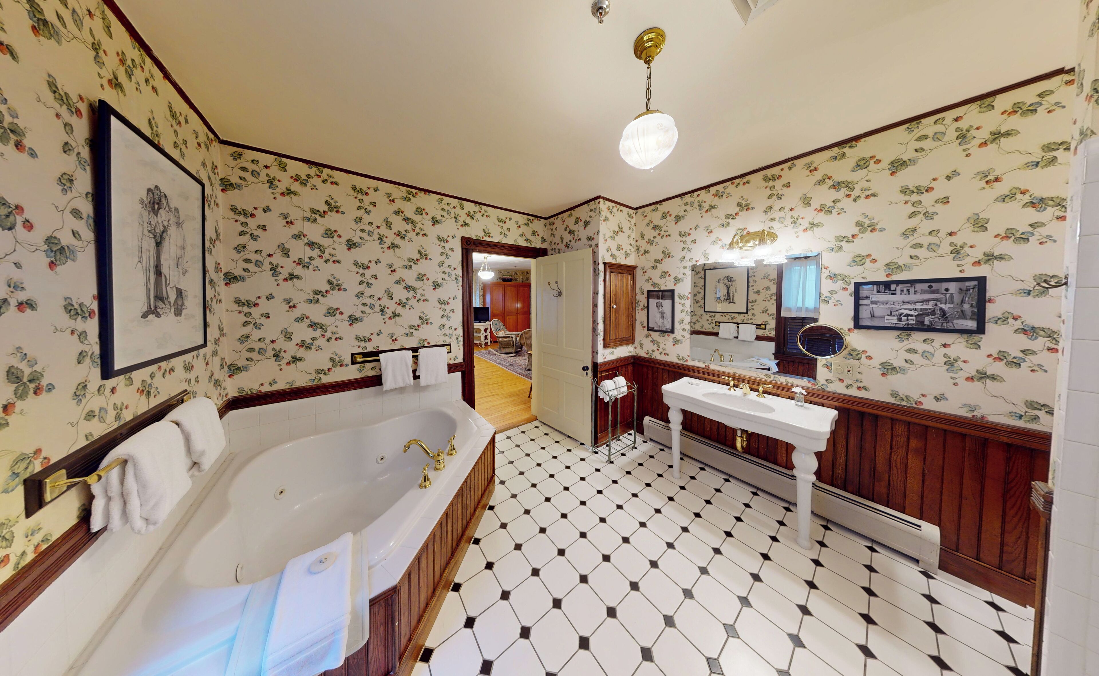 Un baño con una bañera grande, un lavamanos y un espejo. Hay una puerta que conduce a otra habitación.