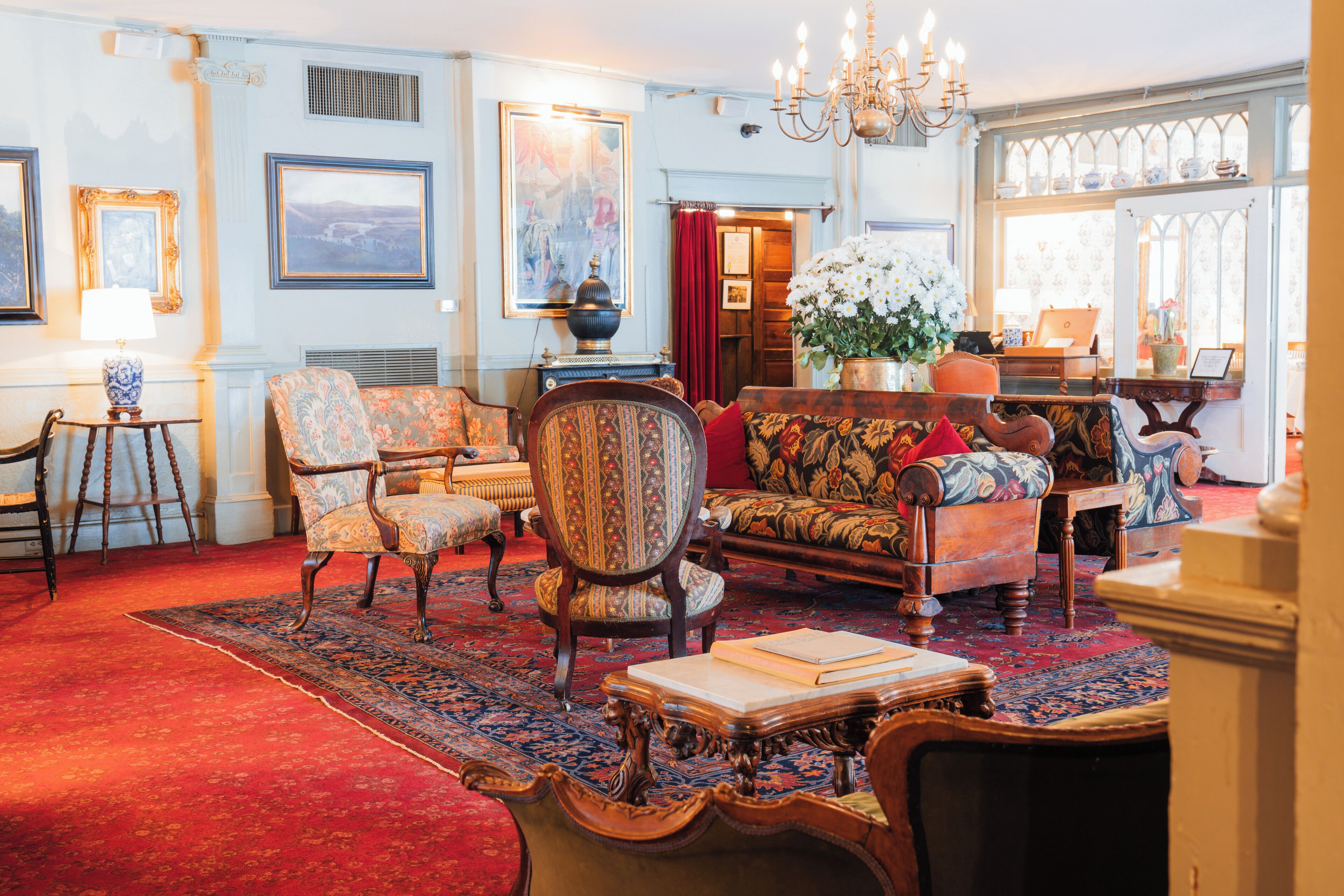 A traditional room with a red carpet, ornate furniture, and a large window with stained glass.