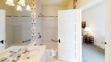 A bathroom with a large mirror, a bathtub, and a shower.