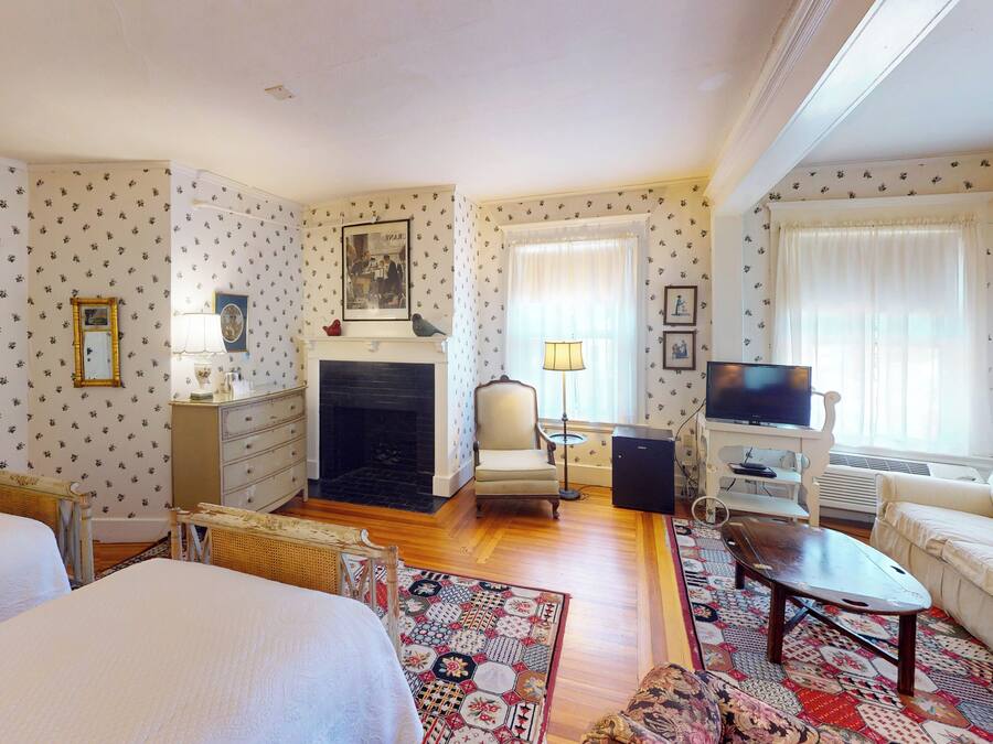 Una habitación de hotel con dos camas, una chimenea, un televisor y un sofá.
