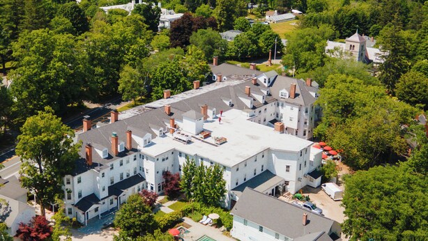 A large, multi-story building with a swimming pool, surrounded by dense greenery and trees. - The Red Lion Inn (Stockbridge)
