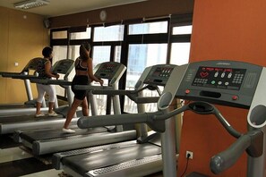 A gym with treadmills, a control panel, and large windows.