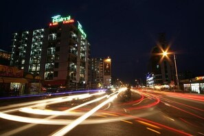 A multi-story hotel with illuminated signage, a busy street with light trails, and a clear night sky. - Haimi Apartment Hotel (Addis Ababa)