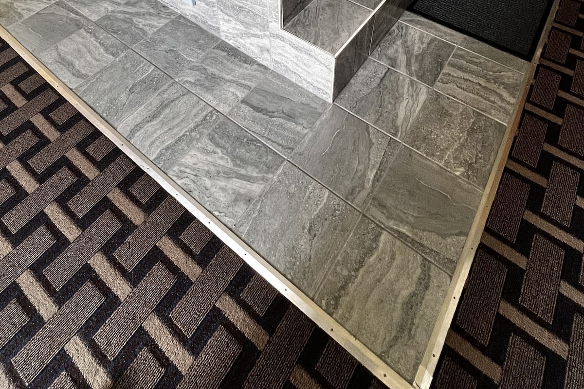 A modern bathroom with a freestanding bathtub, tiled walls, and a patterned floor.