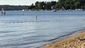 A beach with calm waters, a sandy shore, and a backdrop of houses and trees. - Sky Lodge Inn & Suites (Delavan)