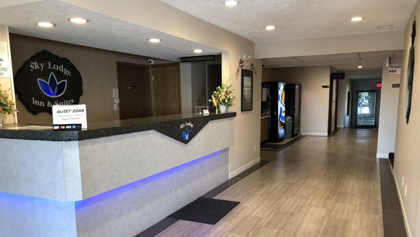 A reception desk at Sky Lodge Inn & Suites with a 'Quiet Zone' sign, a 'Vending' sign, and a 'No Smoking' sign. - Sky Lodge Inn & Suites (Delavan)