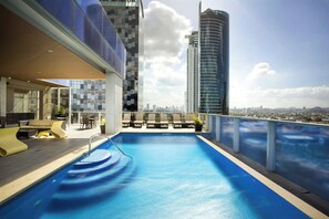 Une piscine sur le toit offrant une vue sur la ville, une architecture moderne et des espaces de détente en plein air.