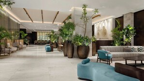 Un hall d’entrée spacieux au design moderne, comprenant un canapé, des fauteuils et de grandes plantes en pot.