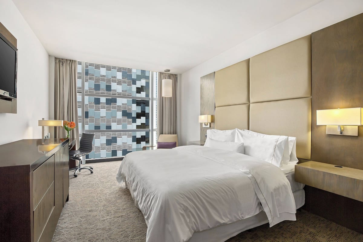 Une chambre d’hôtel moderne avec un grand lit, un bureau et une télévision.