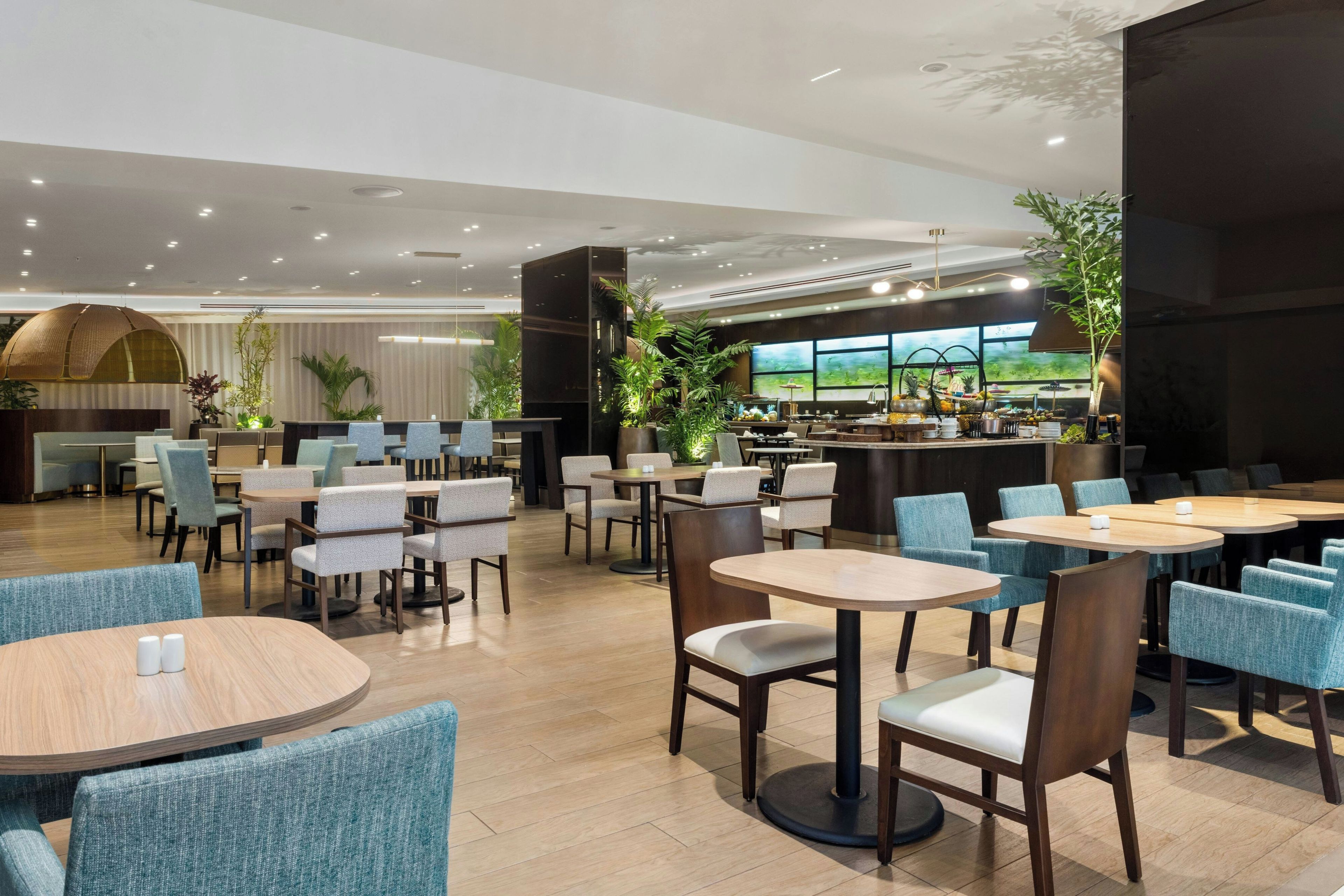 En modern restaurang med runda bord och stolar, en bardisk och stora fönster.