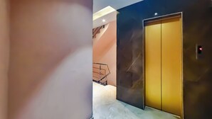 Un interno moderno con una parete in marmo, una scala e un ascensore chiuso.