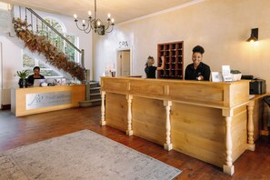 A reception desk with a sign reading 'fresh wellness,' a staircase with a view of trees, and a spa sign in the background.
