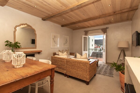 A cozy room with a wooden ceiling, wicker furniture, a large mirror, and a view through an open door. - Auberge Burgundy Guest House (Hermanus)
