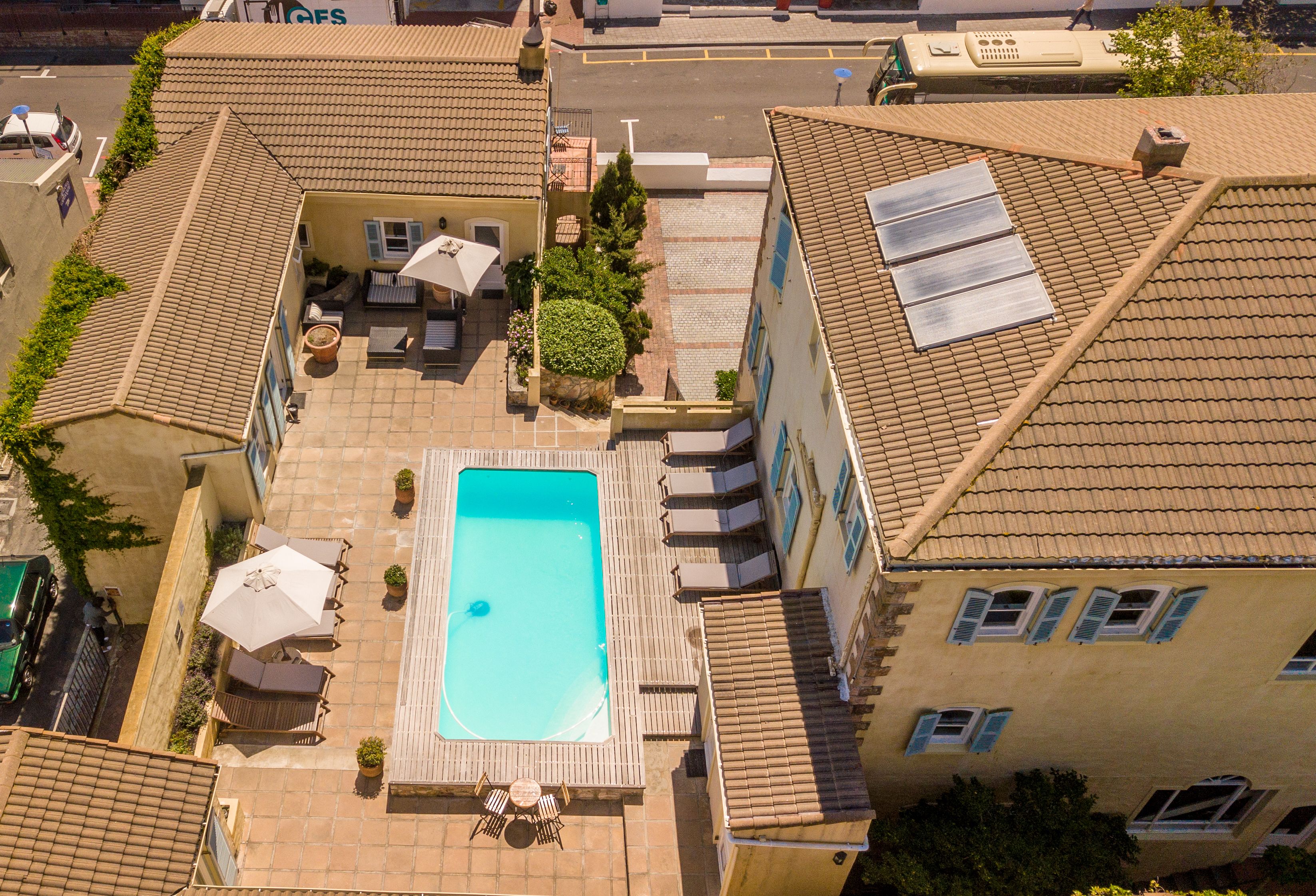 Une piscine sur le toit, avec des chaises longues, une table et un petit espace aménagé en jardin.