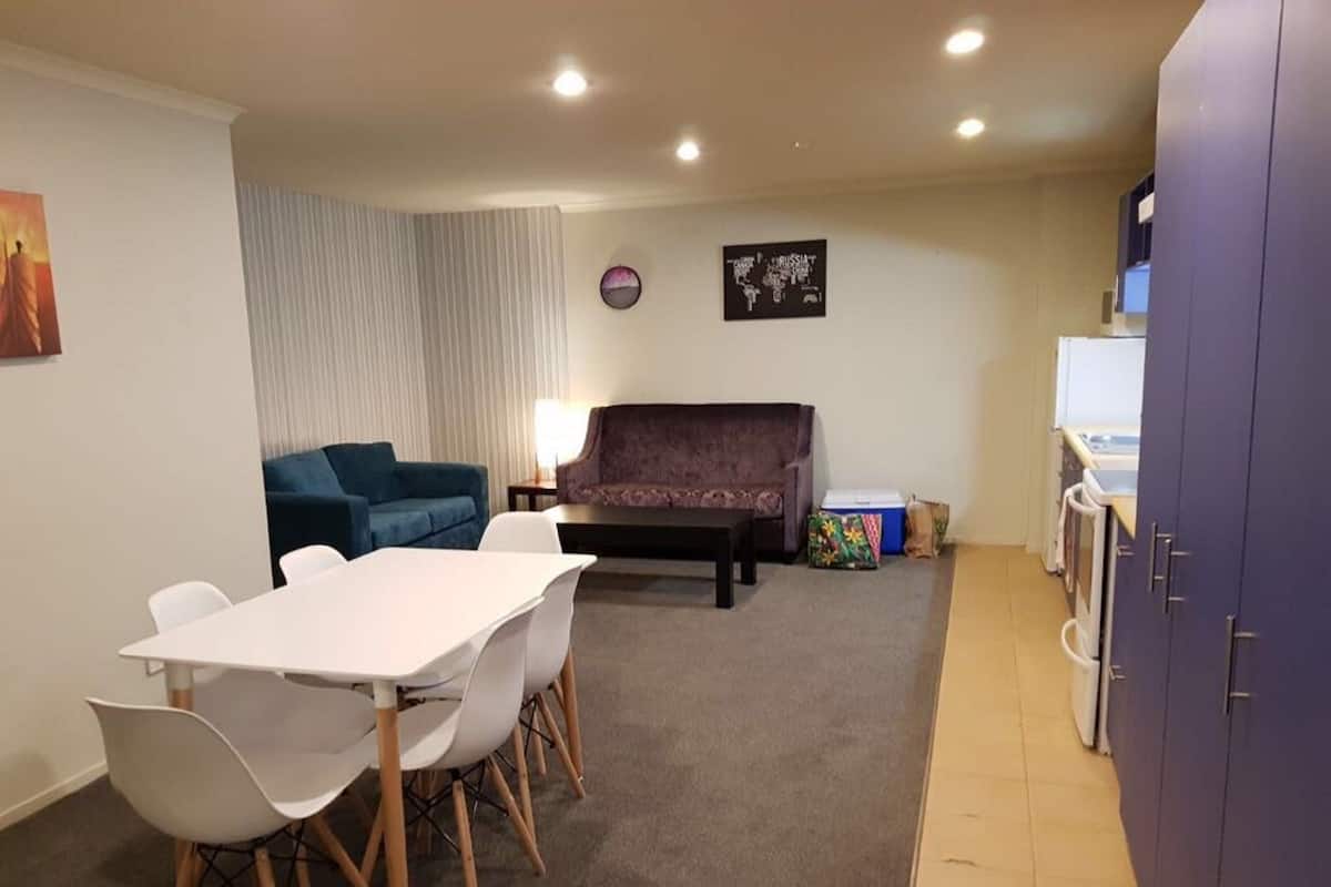 A compact living space with a dining table, two sofas, a small kitchen area, and a wall map.