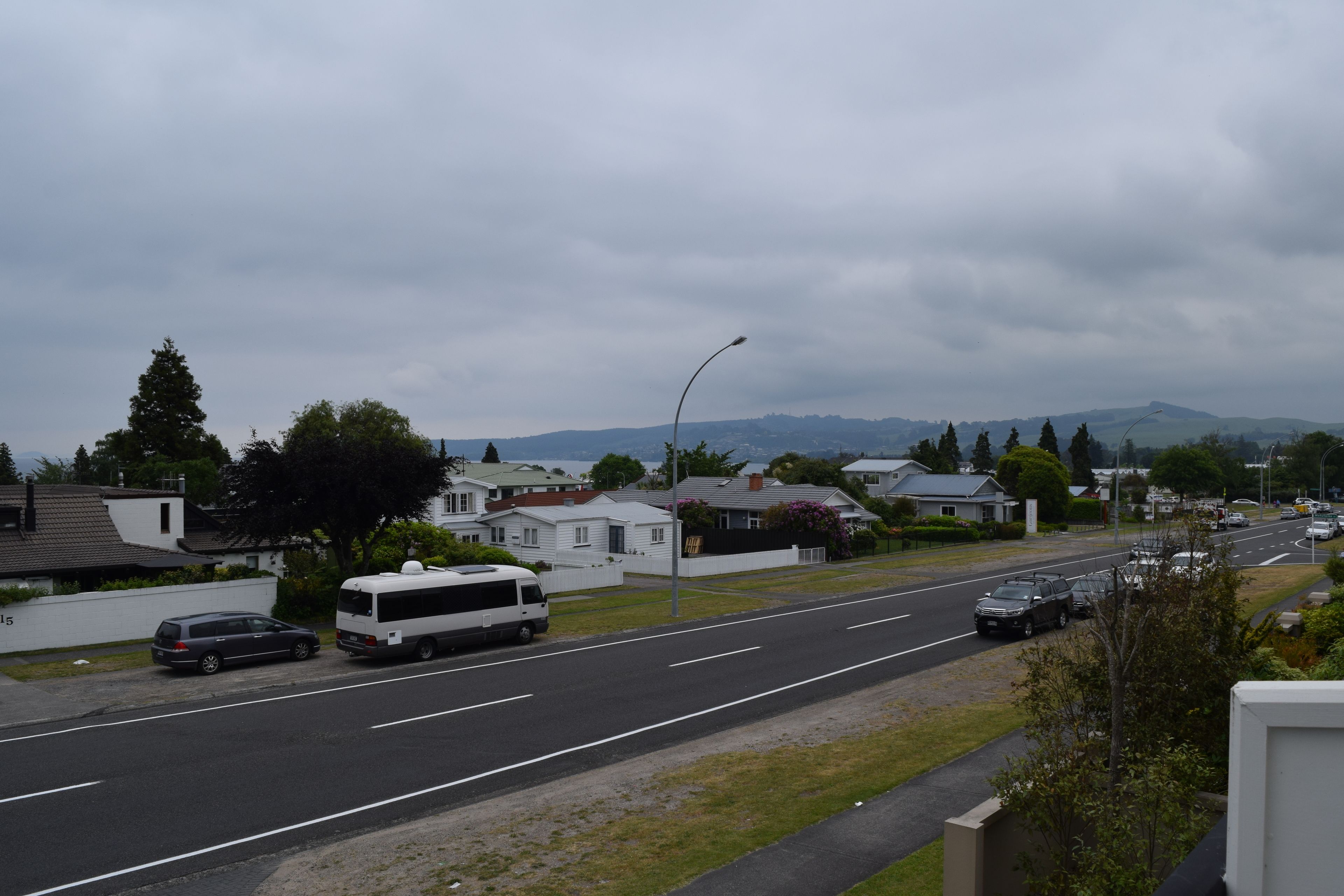 A residential street with houses, a bus, and cars.