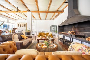 Amplia sala de estar con chimenea, sofás de cuero y una mesa de comedor lista para una comida.