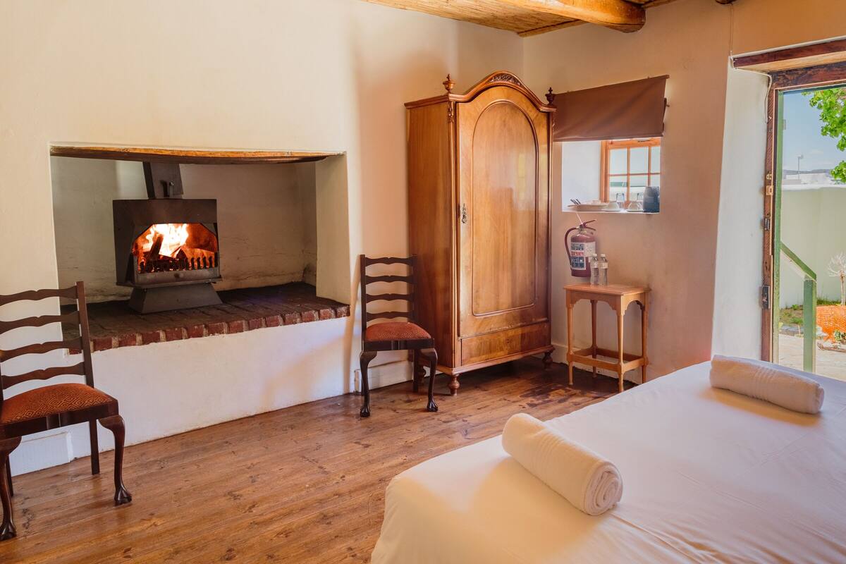 Een kamer met een open haard, houten meubels, een bed en uitzicht door een raam.