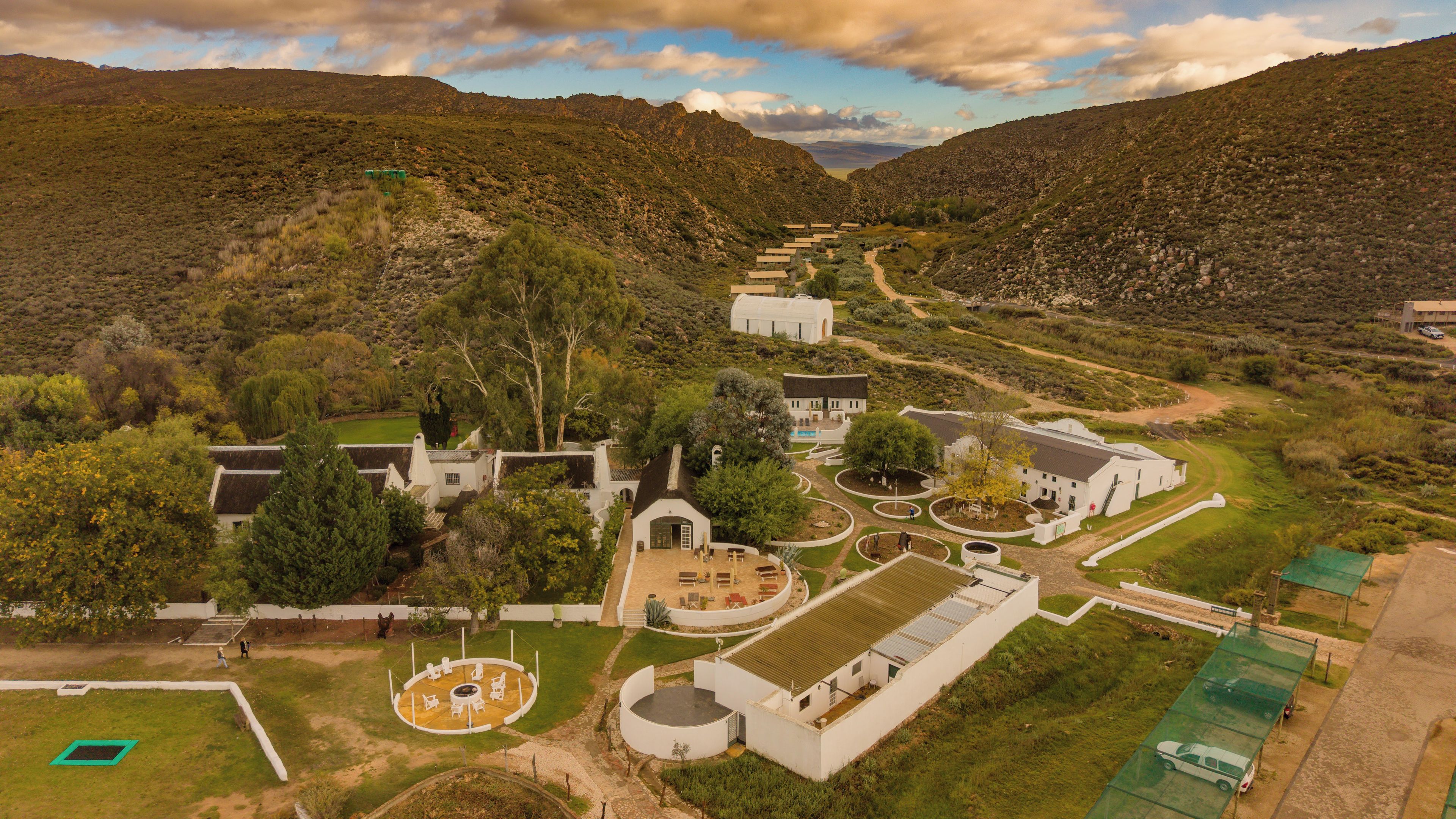 A large estate with multiple buildings, a circular outdoor seating area, and a winding path.