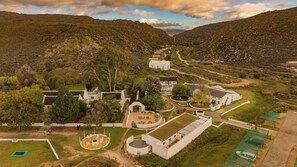 Una extensa propiedad con varios edificios, un espacio exterior circular para sentarse y un sendero sinuoso.