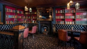 Eine gemütliche Bibliothek mit Bücherregalen, einem Kamin und Ledersitzmöbeln.