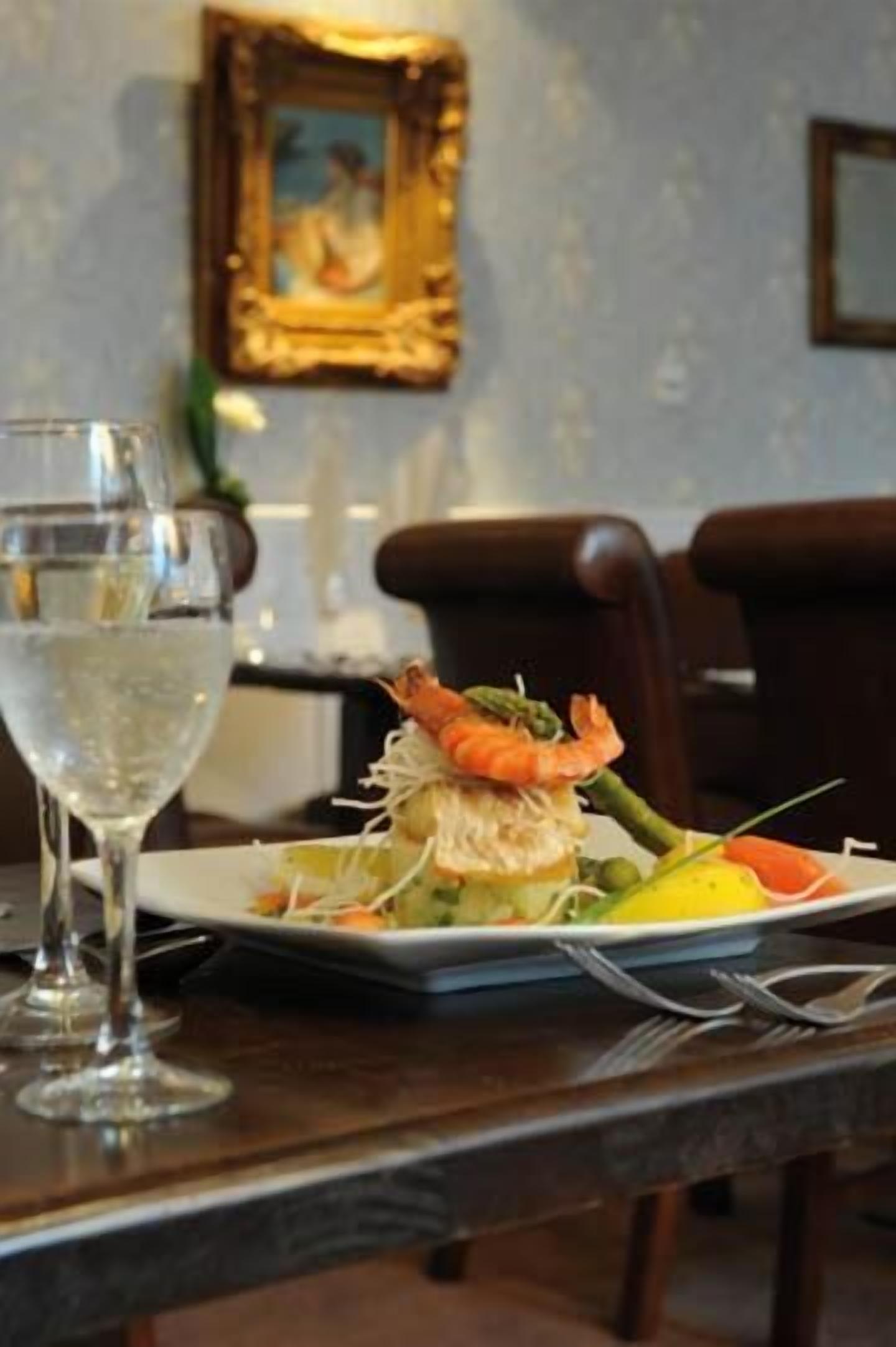 Un tavolo da pranzo con un piatto di cibo, un bicchiere d'acqua e una cornice con un'immagine appesa al muro.