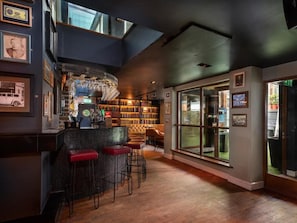Zona de bar con estantería, asientos y vistas a través de un ventanal.