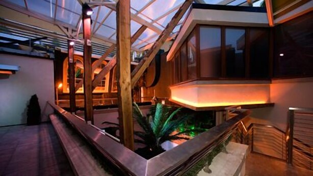 Ein modernes Interieur mit Glasdecke, Holzbalken und einer zentralen Wasserspiele-Anlage.