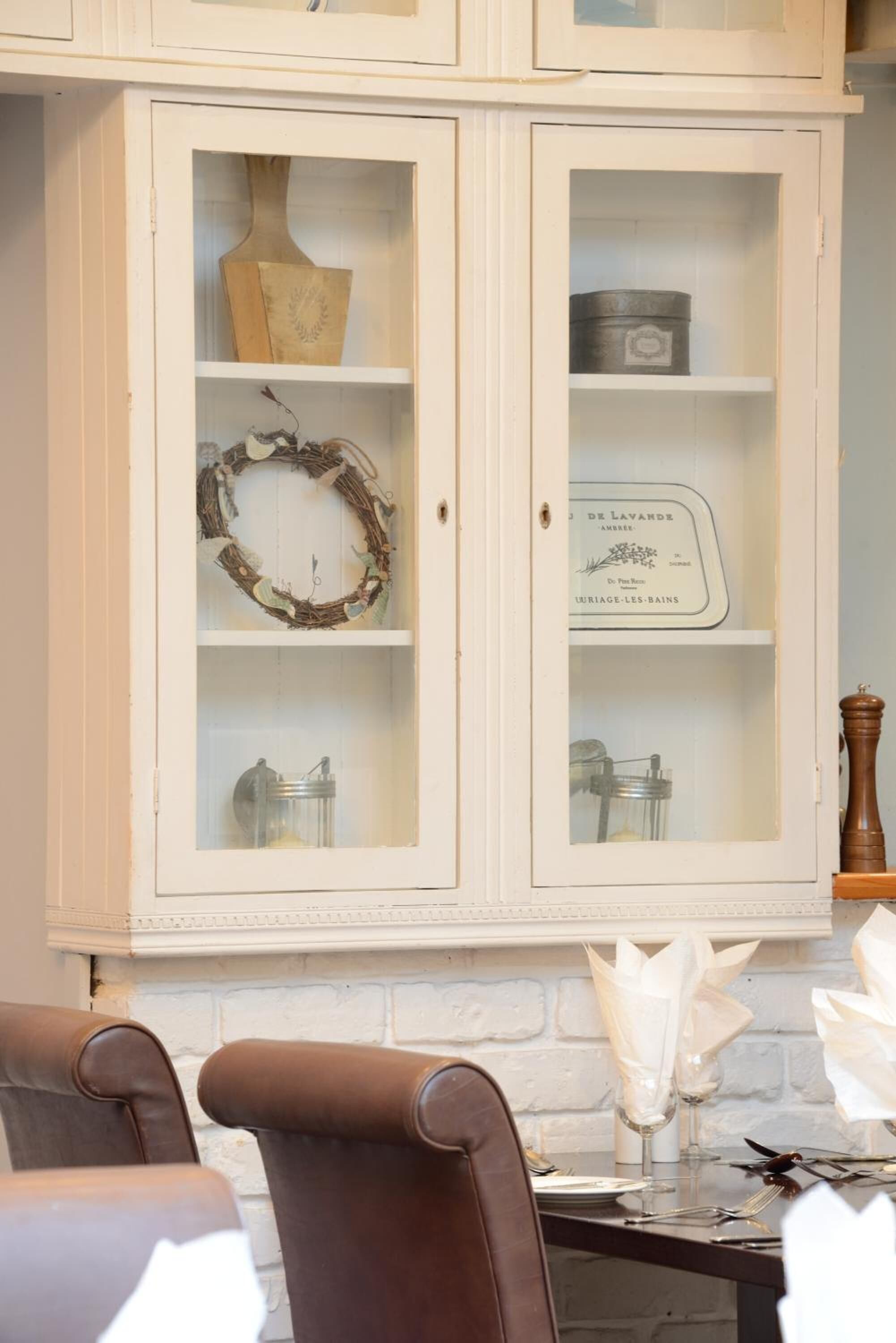 A dining area with a white cabinet containing decorative items and a table set for dining.