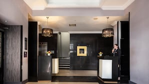 Eine moderne Hotellobby mit einer Rezeption, einer Treppe und einem Chandelier.