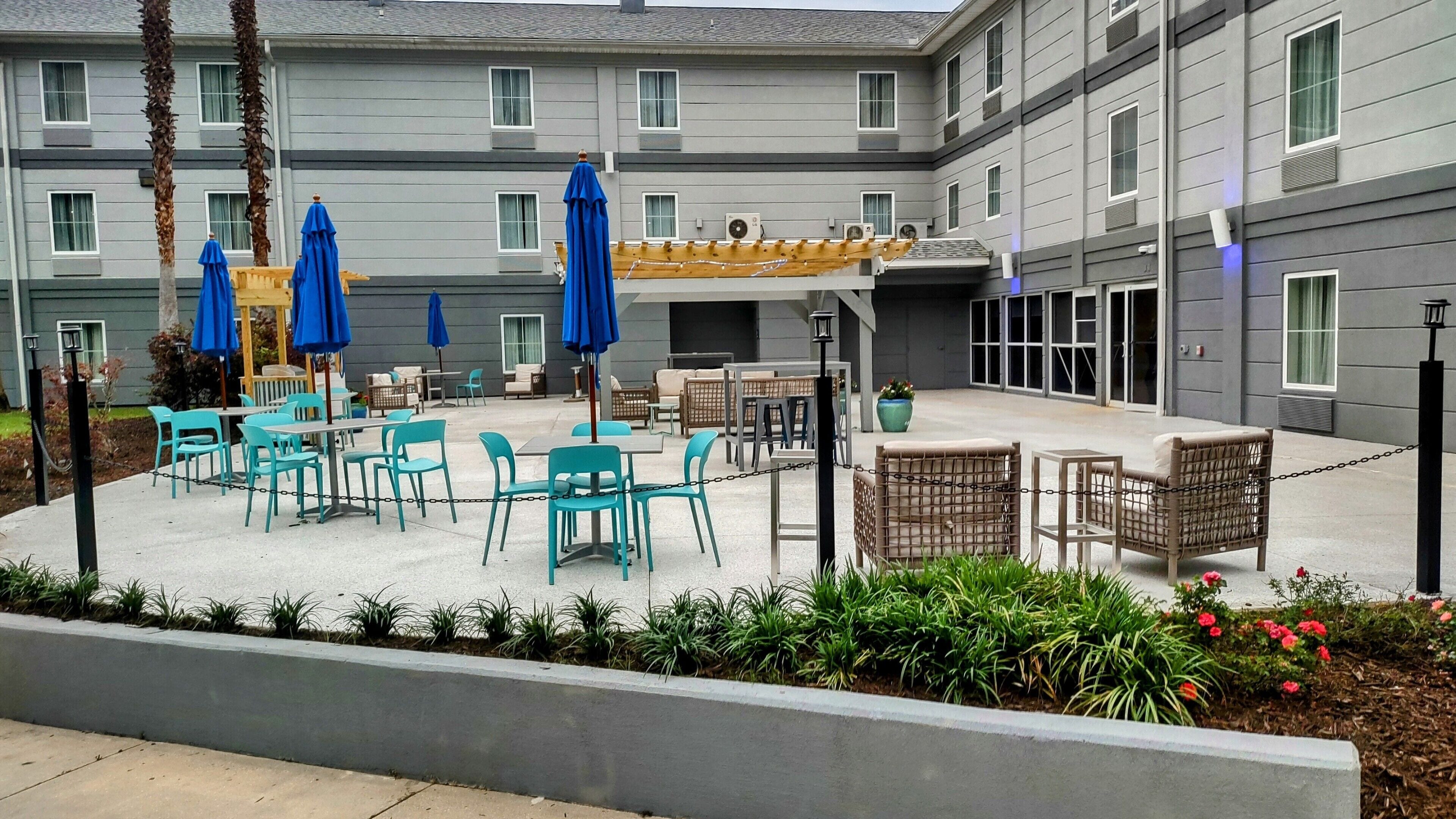 A hotel courtyard with outdoor seating, including tables and chairs, and covered areas with umbrellas.