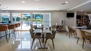 A modern dining area with tables and chairs, large windows, and a view of the outdoors.