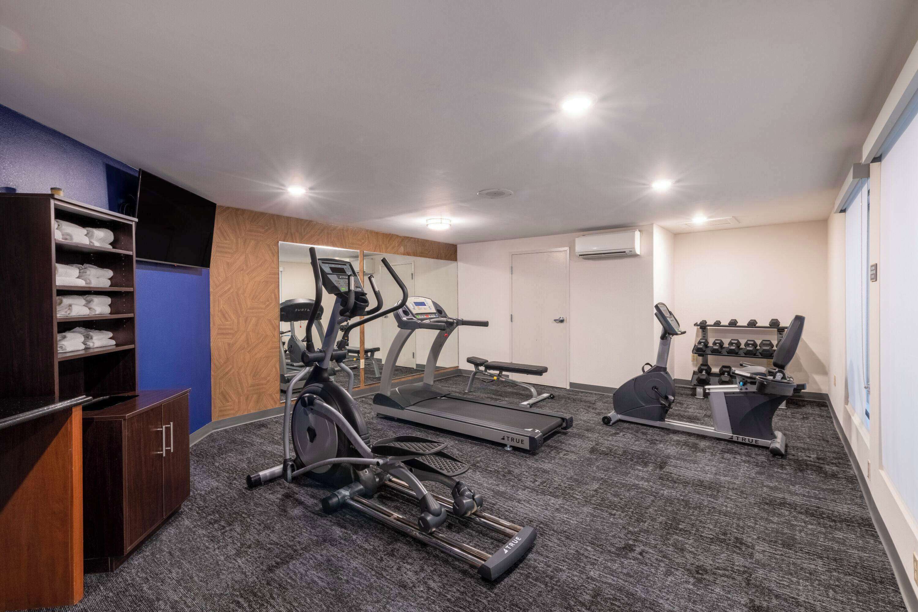 A gym with treadmills, an elliptical, and free weights.
