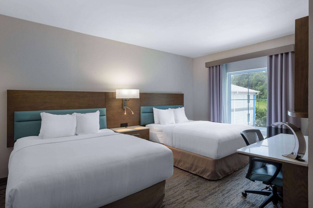 Une chambre d’hôtel avec deux lits, un bureau et une chaise.