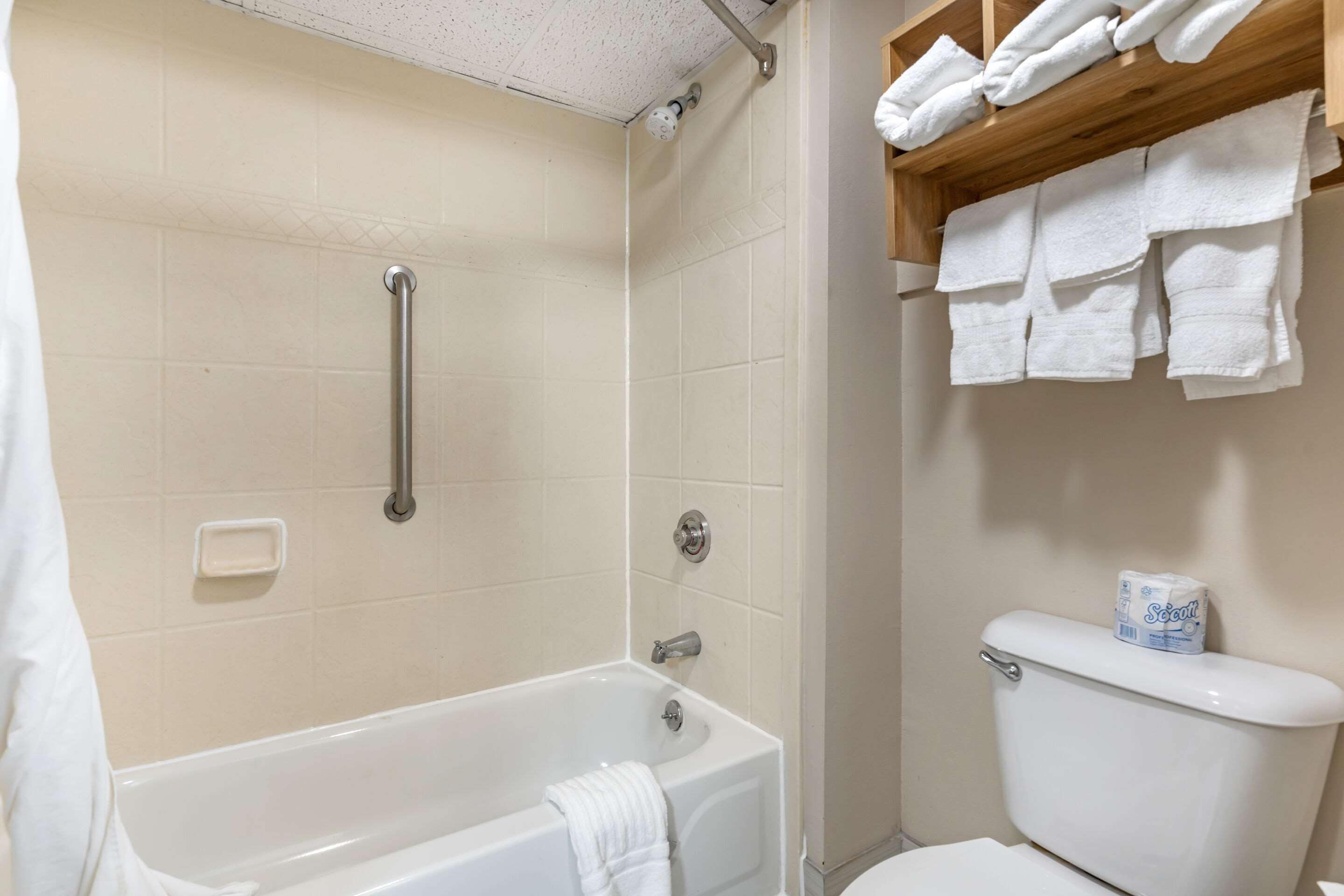 Une salle de bain avec une baignoire, des toilettes et une étagère avec des serviettes.