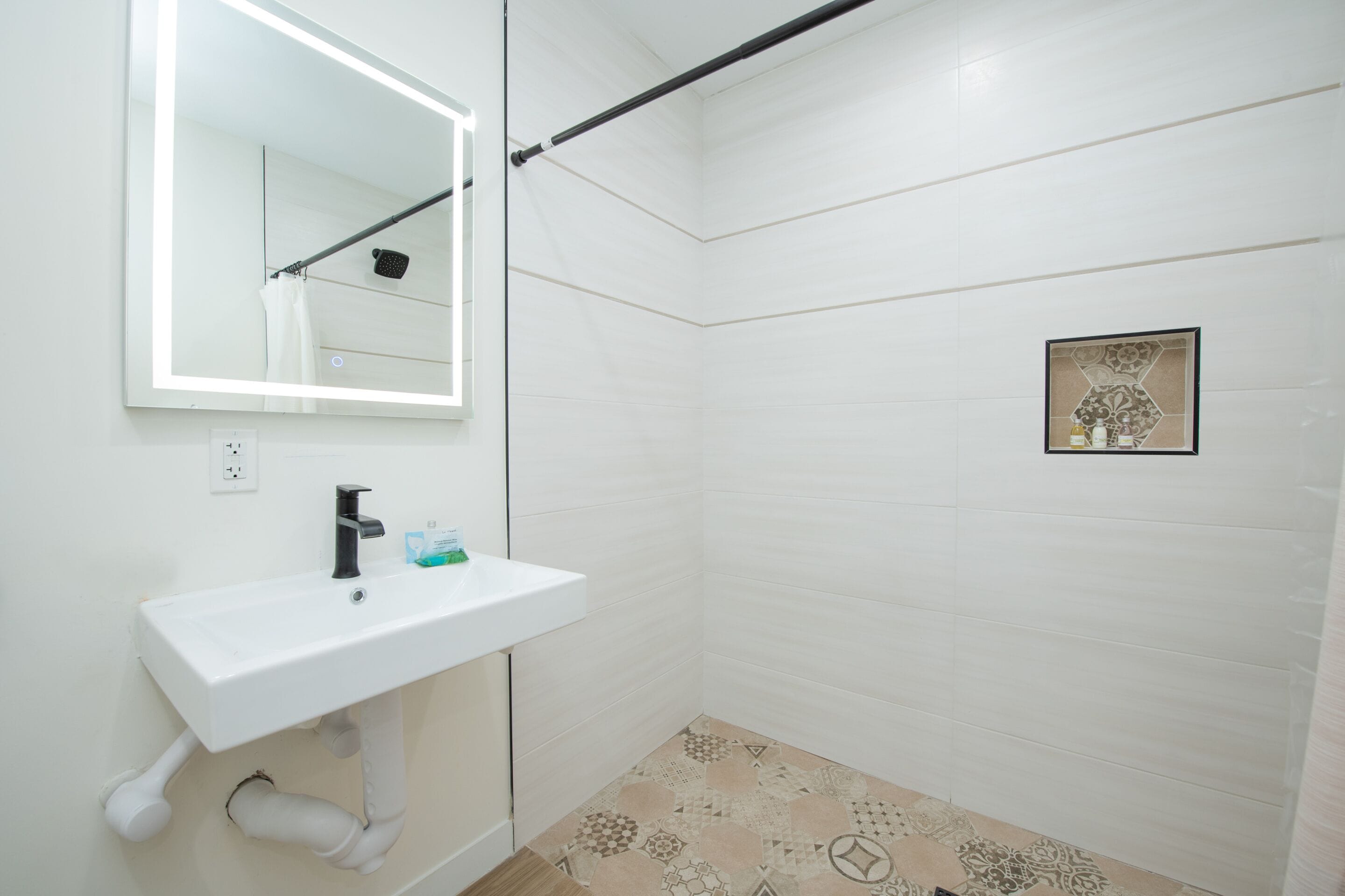 A bathroom with a white sink, a mirror, and a shower area.