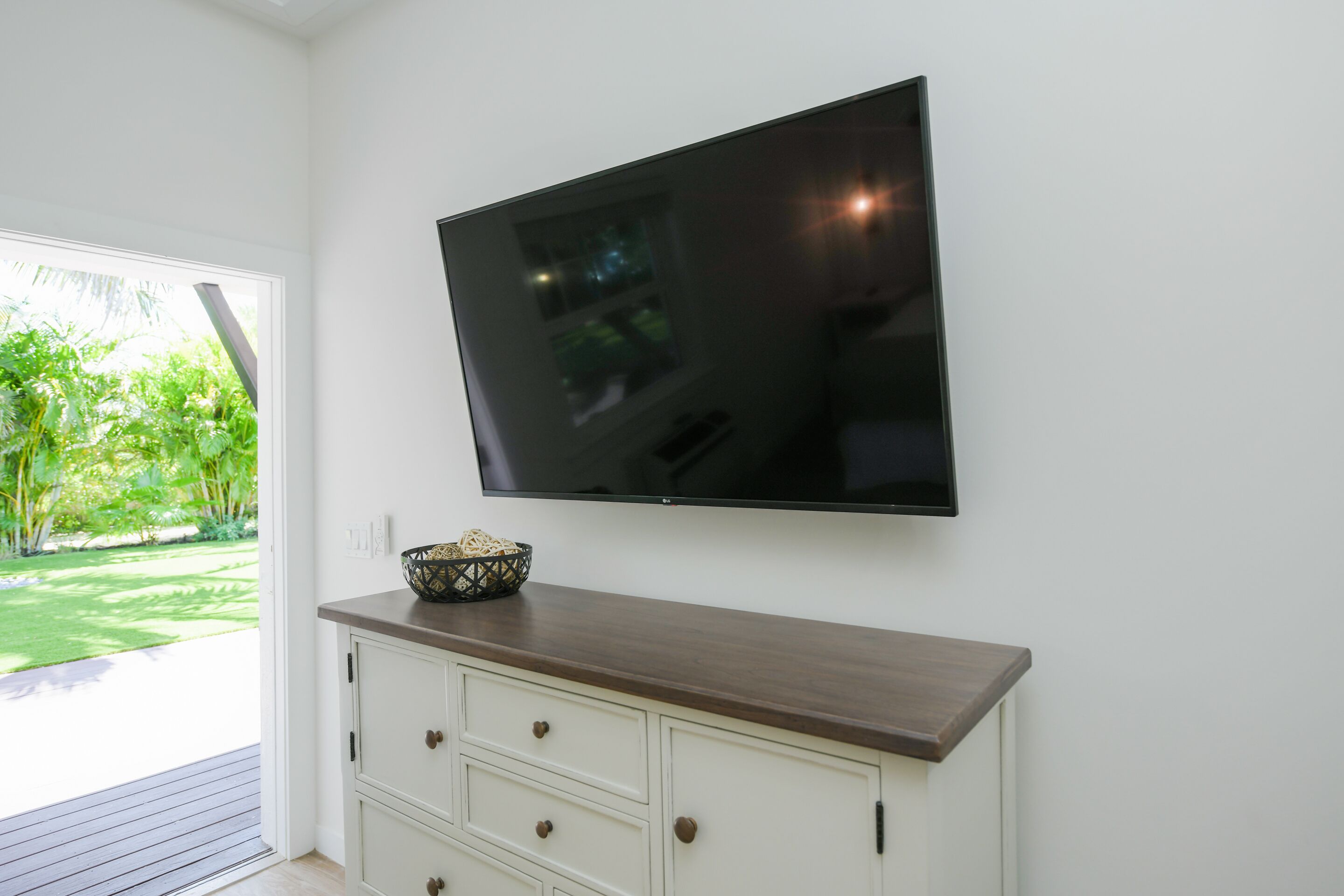 Una habitación con un televisor de pantalla plana montado en la pared, encima de un mueble de madera con cajones.