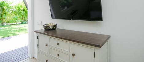 Una habitación con un televisor de pantalla plana montado en la pared, encima de un mueble de madera con cajones.