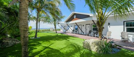 A modern house with a patio, outdoor seating, and a view of the ocean.
