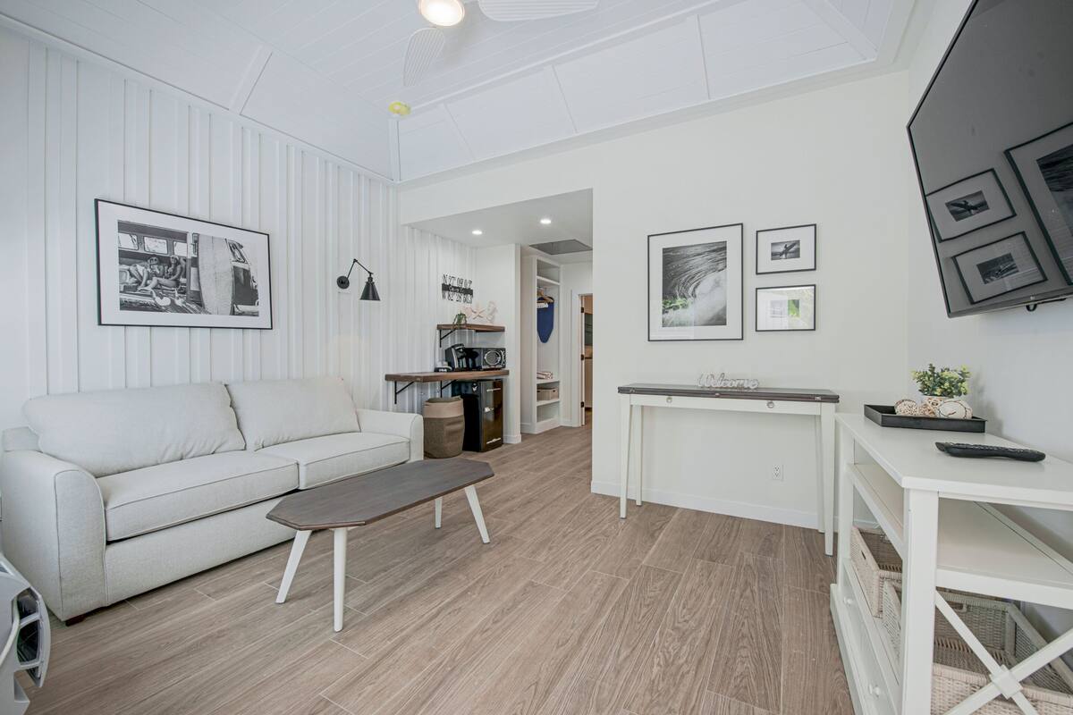 A modern living room with a white sofa, a coffee table, and a dining area with a white table and chairs.