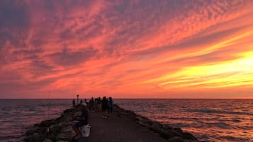 Ein Sonnenuntergang über einem steinernen Steg, an dem Menschen angeln.