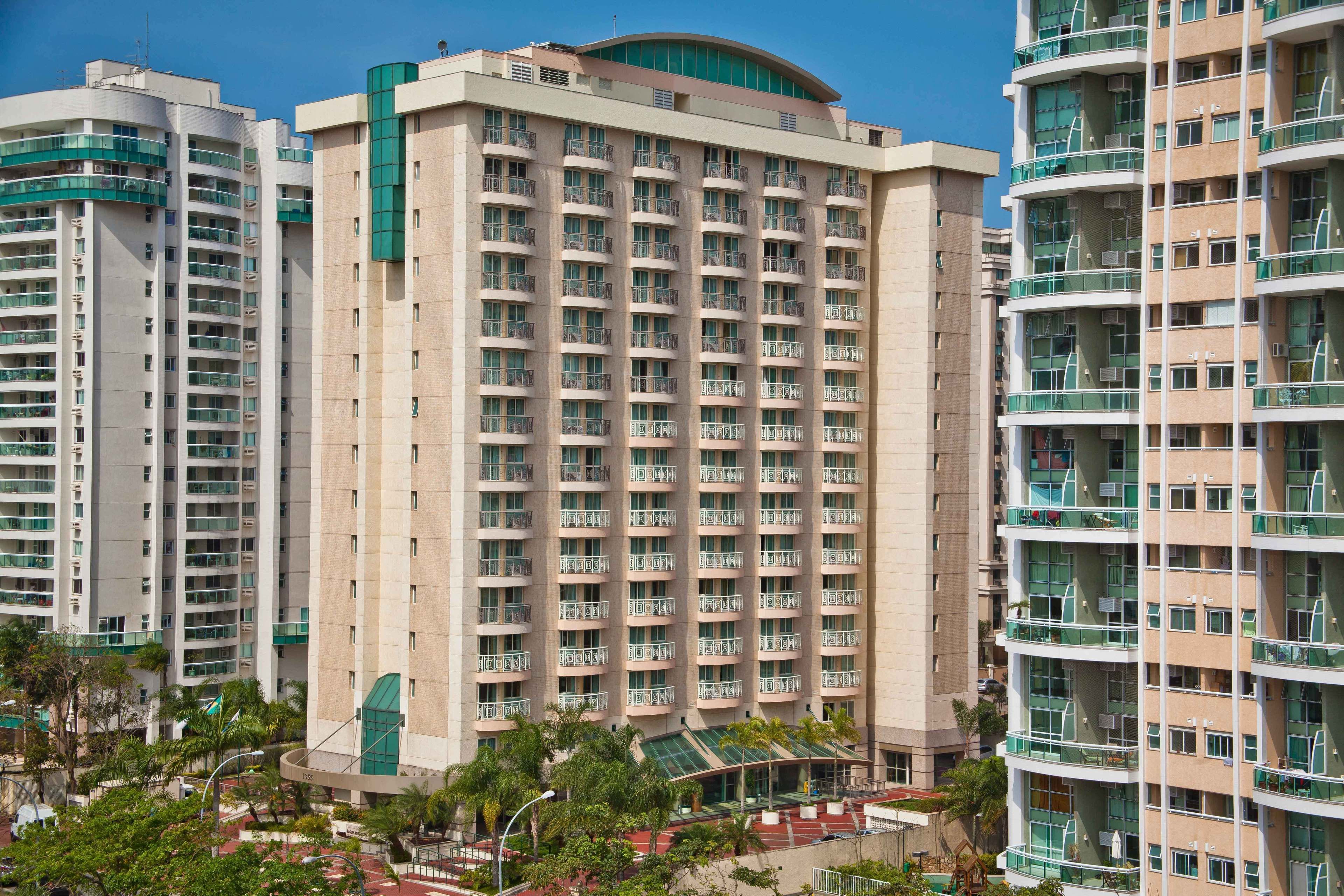 Un hôtel à plusieurs étages doté d’un atrium central, de balcons à chaque étage et d’un espace paysager aménagé tout autour.