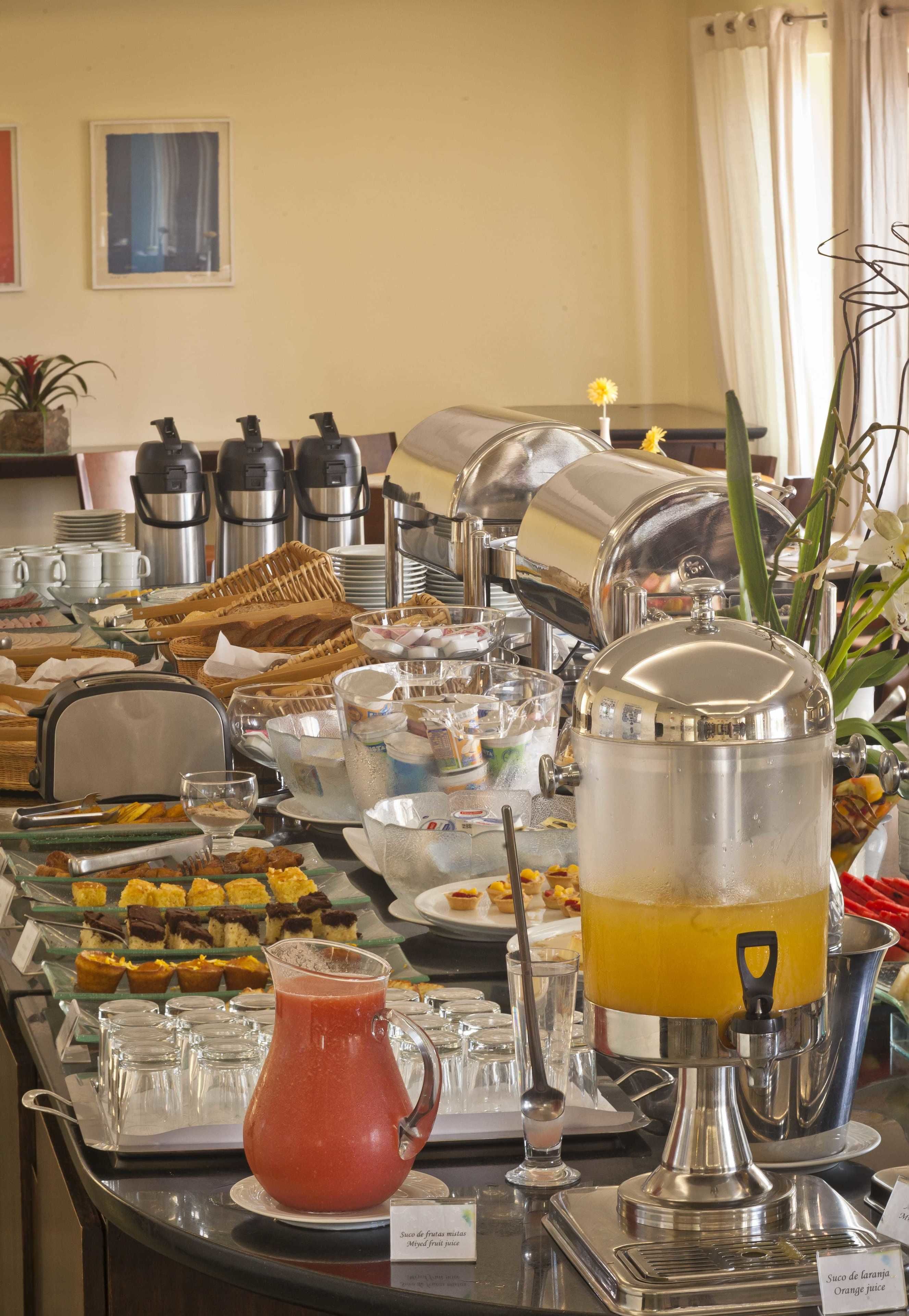 A buffet setup with various food items, a juice dispenser, and coffee makers.